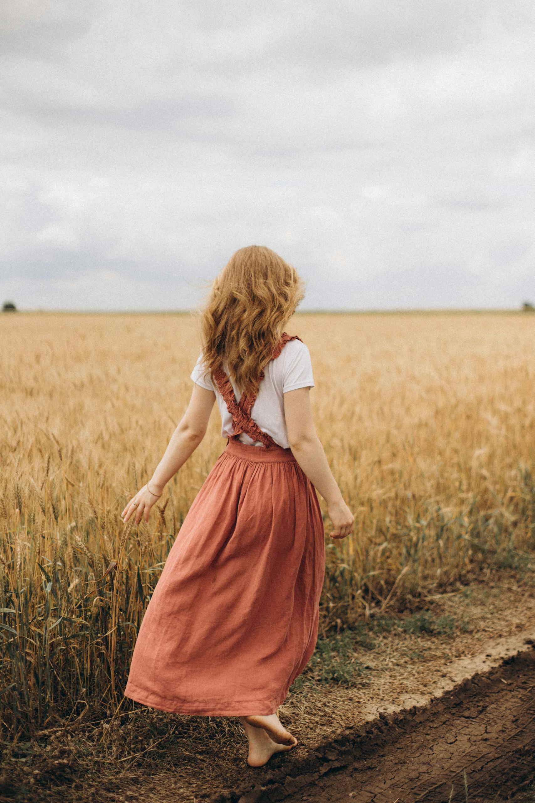 Woman in White T-Shirt and Skirt Walking in Golden Field